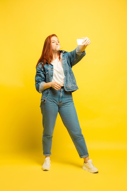 Łatwiej jest być naśladowcą. Potrzebujesz minimum ubrań do selfie. Portret kobiety kaukaski na żółtym tle. Piękne kobiece włosy model. Pojęcie ludzkich emocji, wyraz twarzy, sprzedaż, reklama.