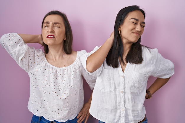 Latynoska matka i córka razem cierpią z powodu bólu szyi, dotykając szyi ręką, ból mięśni