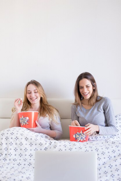 Laughing kobiet oglądania filmu w łóżku