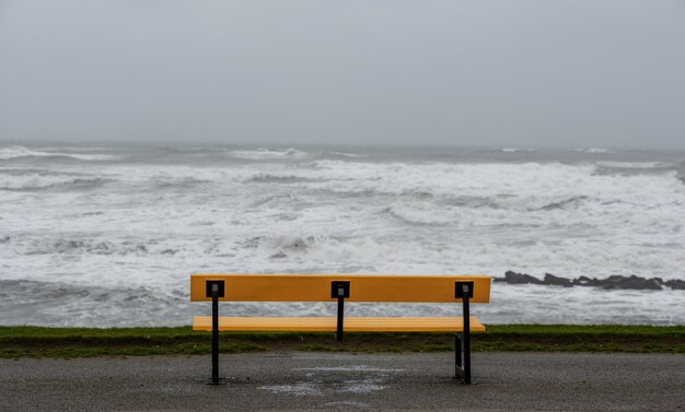 Ławka na plaży otoczonej morzem pod zachmurzonym niebem podczas burzy