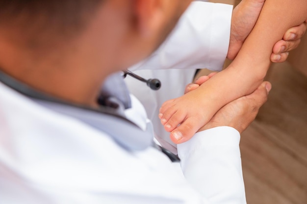 Lekarz bada stopy dzieci w szpitalu. chirurg, traumatolog lub ortopeda dotykający nogi i stopy dziewczynki