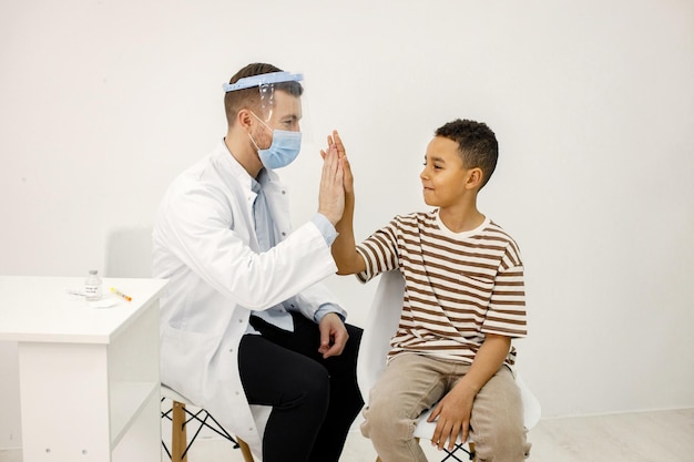 Bezpłatne zdjęcie lekarz mężczyzna przybija piątkę chłopcu po szczepieniu