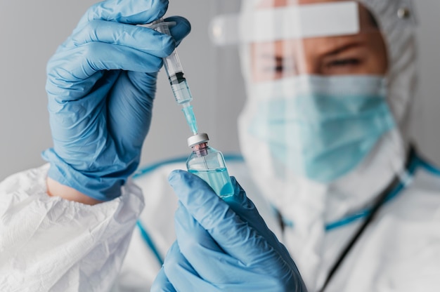 Lekarz posiadający przygotowanie szczepionki nosząc sprzęt ochronny