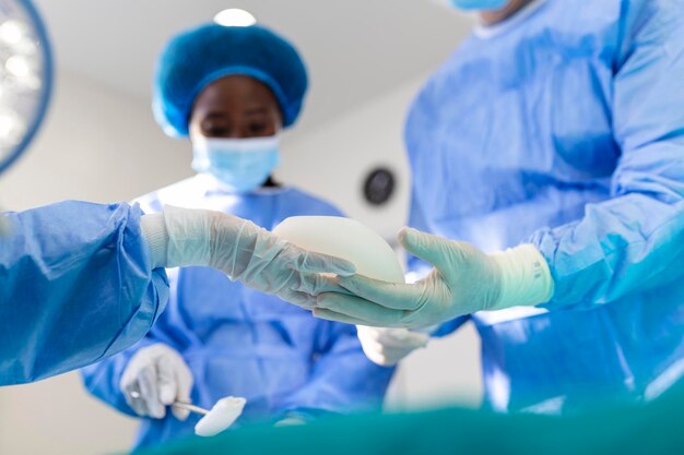 Lekarz posiadający silikonowy implant medyczny Chirurg trzyma silikonowy implant i zainstaluj w kobiecie zbliżenie biustu Interwencja chirurgiczna koncepcja biznesowa powiększania piersi