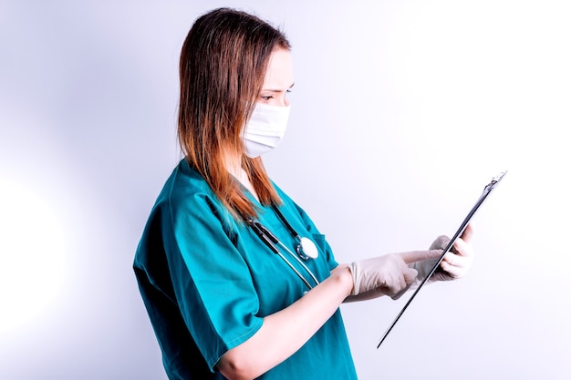 Lekarz szpitalny w rękawiczkach z maską na białym tle czyta pełny raport lekarski