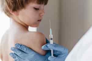 Bezpłatne zdjęcie lekarz w rękawiczkach wykonujący szczepionkę na małe dziecko