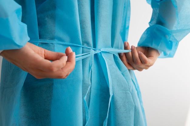 Bezpłatne zdjęcie lekarz wiążący widok z boku na pasek sukni medycznej