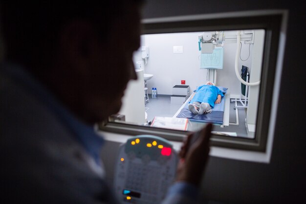 Lekarz za pomocą panelu kontrolnego aparatu rentgenowskiego na pacjencie