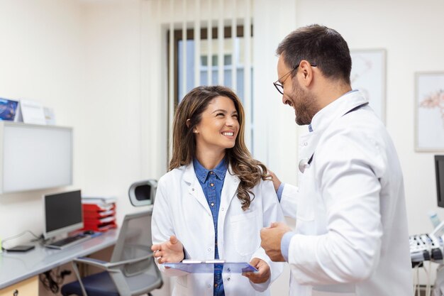 Lekarze dyskutują nad raportem medycznym w szpitalu Lekarz płci żeńskiej i męskiej sprawdza raport kliniczny pacjenta online Personel opieki zdrowotnej prowadzi dyskusję w gabinecie prywatnej kliniki