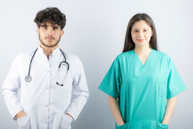 Lekarze płci męskiej i żeńskiej stojąc i patrząc na kamery.