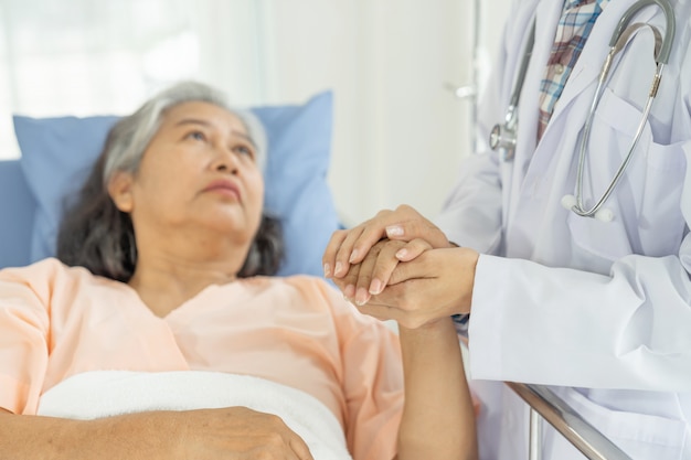 Lekarze trzymają się za ręce, aby zachęcić pacjentów w podeszłym wieku do starszej kobiety w szpitalu