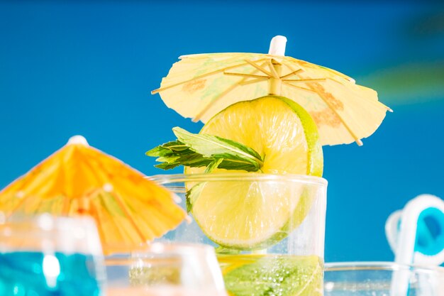 Lekki napój z plasterkami limonki i mięty w szklance zdobionej parasolem