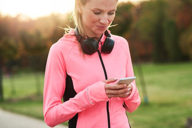 Lekkoatletka przy użyciu telefonu komórkowego podczas treningu joggingu