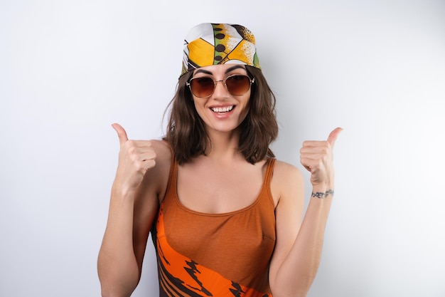 Letni portret młodej kobiety w sportowym stroju kąpielowym, chustce i okularach przeciwsłonecznych