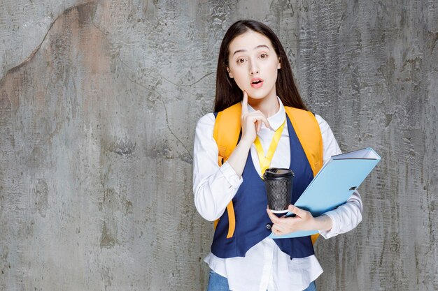 Liceum dziewczyna trzyma filiżankę kawy i folder. Zdjęcie wysokiej jakości