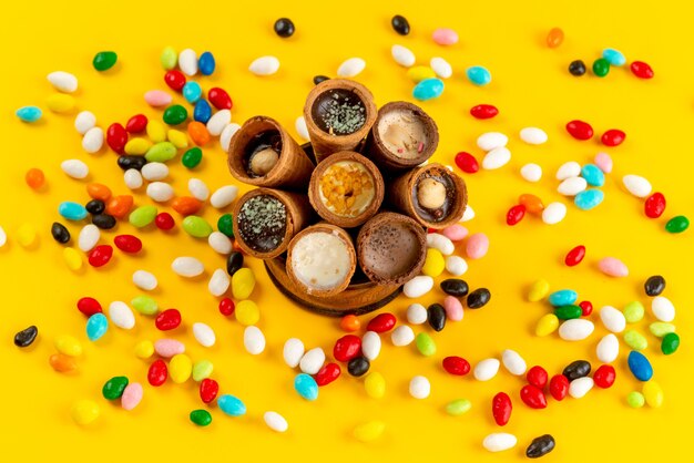 Lody z widokiem z góry i kolorowe cukierki rozprowadzone na żółtym słodkim cukrze w kolorze podłogi