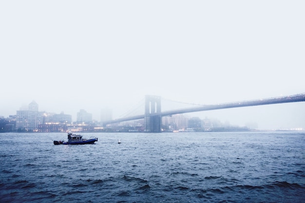 Łódź na wodzie w pobliżu mostu wantowego podczas mglistej pogody