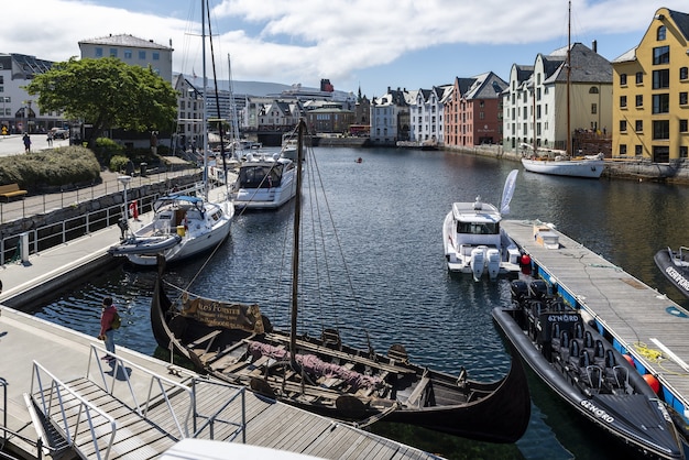 Łodzie na szerokim kanale wodnym otoczonym kolorowymi budynkami w Alesund w Norwegii