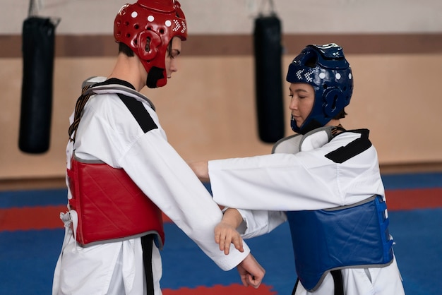 Bezpłatne zdjęcie ludzie ćwiczący taekwondo w sali gimnastycznej