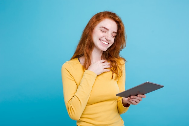 Ludzie i koncepcji technologii - Zamknij w górę Portret młodych piękne atrakcyjne redhair dziewczyna szczęśliwy uśmiecha się na cyfrowe tabeli z wining coś. Niebieskie Tło Pastelowe. Skopiuj miejsce.