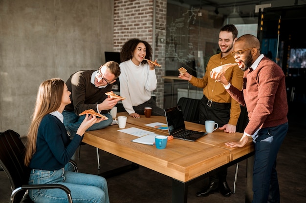 Ludzie jedzący pizzę podczas przerwy na spotkanie w biurze
