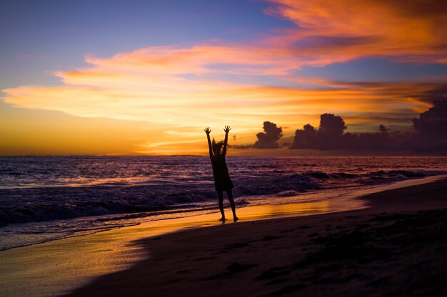 ludzie na plaży o zachodzie słońca. dziewczyna skacze