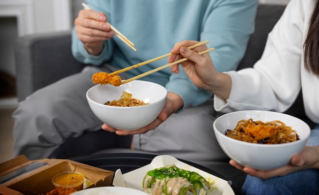 Bezpłatne zdjęcie ludzie pod dużym kątem jedzący azjatyckie jedzenie