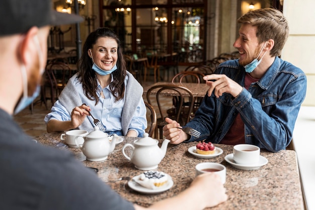 Ludzie rozmawiający w restauracji z maskami na twarz