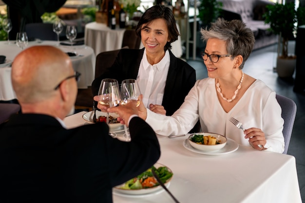 Bezpłatne zdjęcie ludzie wiwatujący kieliszkami do wina w luksusowej restauracji