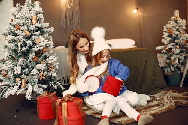 Ludzie wynagradzający święta. matka bawi się z córką. rodzina odpoczywa w świątecznym pokoju. dziecko w niebieskim swetrze.