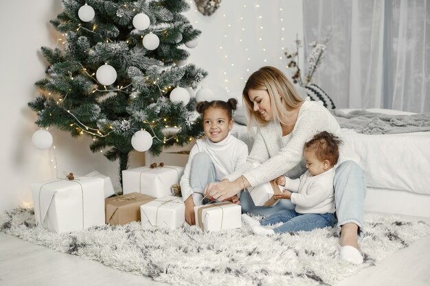 Ludzie wynagradzający święta. Matka bawi się z córkami. Rodzina odpoczywa w świątecznym pokoju. Dziecko w swetrze sweter.