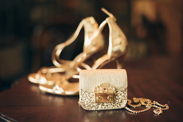 Luksusowe dodatki damskie, złote buty na obcasie, mała torebka wieczorowa, elegancki styl, styl vintage, sandały obuwie