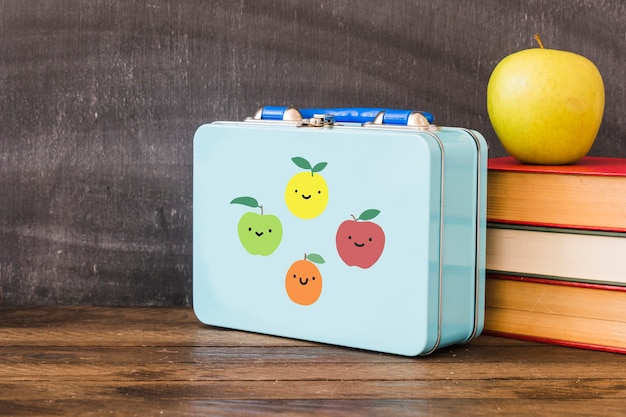 Lunchbox w pobliżu stosu książek i jabłka