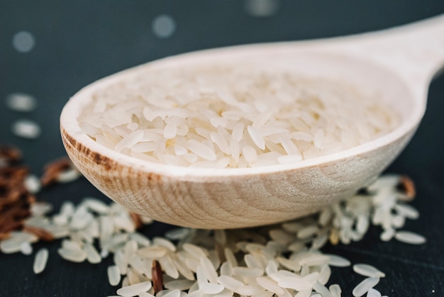 Bezpłatne zdjęcie Łyżka z ryżem na rozlanych ziarnach