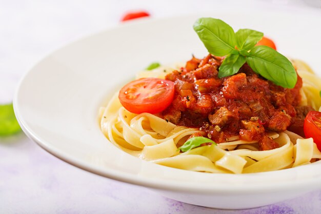 Makaron Fettuccine Bolognese z sosem pomidorowym w białej misce.