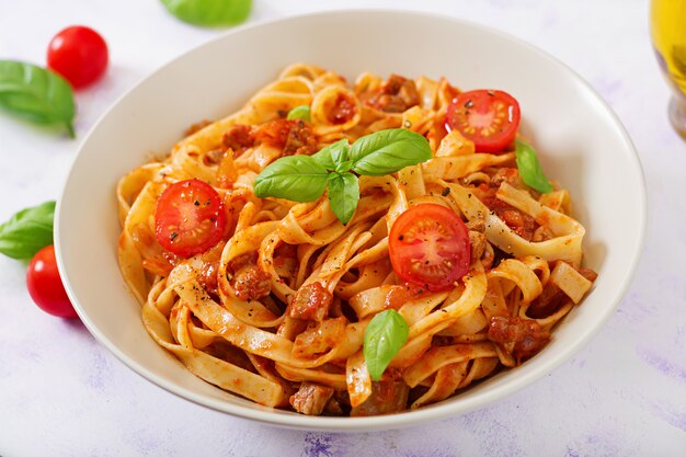 Makaron Fettuccine Bolognese z sosem pomidorowym w białej misce.