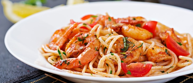 Makaron spaghetti z krewetkami, pomidorem i natką pietruszki. Zdrowy posiłek. Włoskie jedzenie.