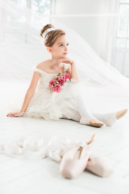 Mała balerina w białej spódniczce baletnicy w klasie na balecie