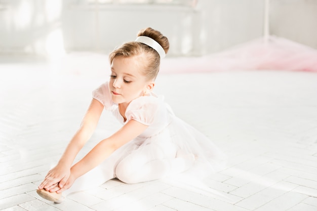 Mała baleriny dziewczyna w spódniczce baletnicy. Urocze dziecko tańczy klasyczny balet w białym studiu.