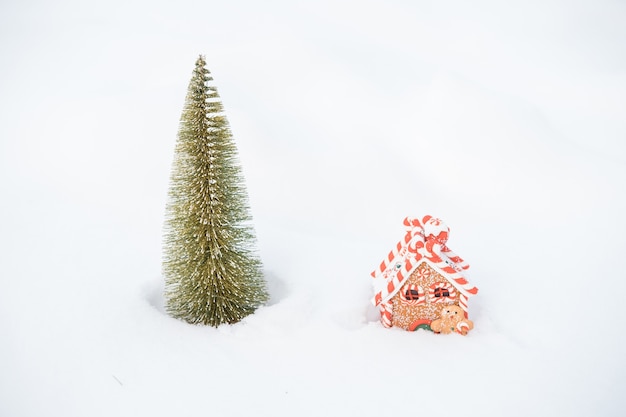 Mała choinka i piernikowy domek w śniegu na świeżym powietrzu. wesołych świąt. szczęśliwego nowego roku. zdjęcie wysokiej jakości