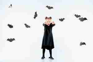 Bezpłatne zdjęcie mała czarownica dziewczyna w czarnej długiej sukni i magicznych akcesoriach