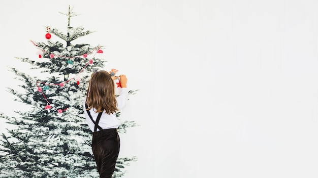 Bezpłatne zdjęcie mała dziewczynka dekoruje choinki