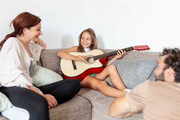 Mała dziewczynka gra na gitarze dla swoich rodziców