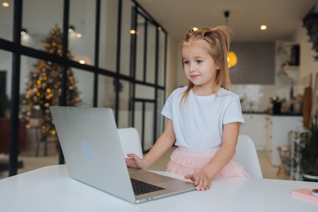Mała dziewczynka korzystająca z komputera typu tablet, siedząca przy stole
