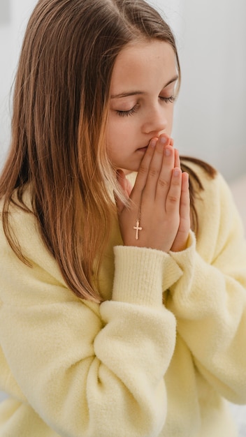Mała dziewczynka modli się z krzyżem naszyjnik