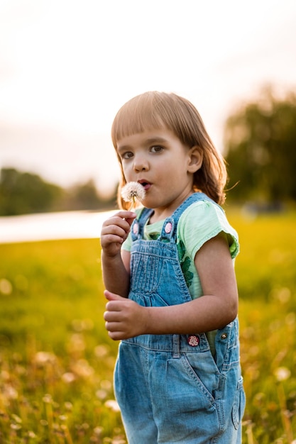 Mała dziewczynka na dandelion polu przy zmierzchem, emocjonalny szczęśliwy dziecko.