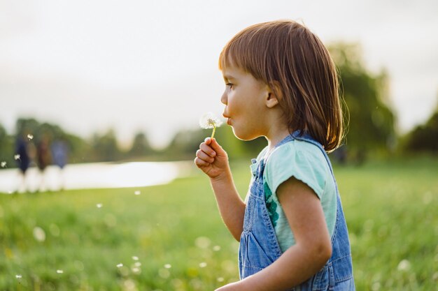 Mała dziewczynka na dandelion polu przy zmierzchem, emocjonalny szczęśliwy dziecko.