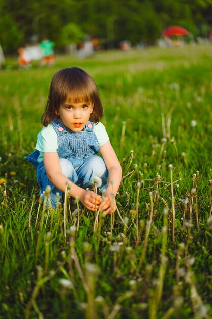 Mała dziewczynka na dandelion polu przy zmierzchem, emocjonalny szczęśliwy dziecko.