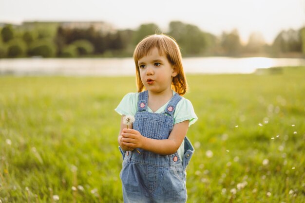 Mała dziewczynka na dandelion polu przy zmierzchem, emocjonalny szczęśliwy dziecko.