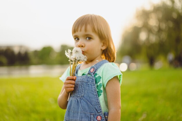 Mała dziewczynka na dandelion polu przy zmierzchem, emocjonalny szczęśliwy dziecko.